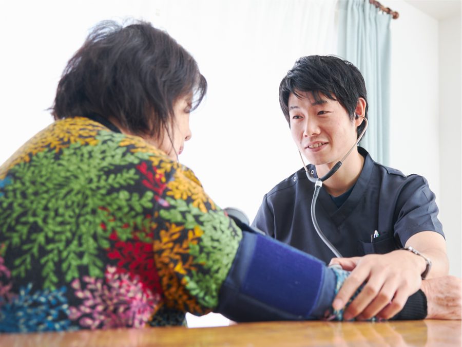 自宅で利用者の血圧を測る訪問看護師