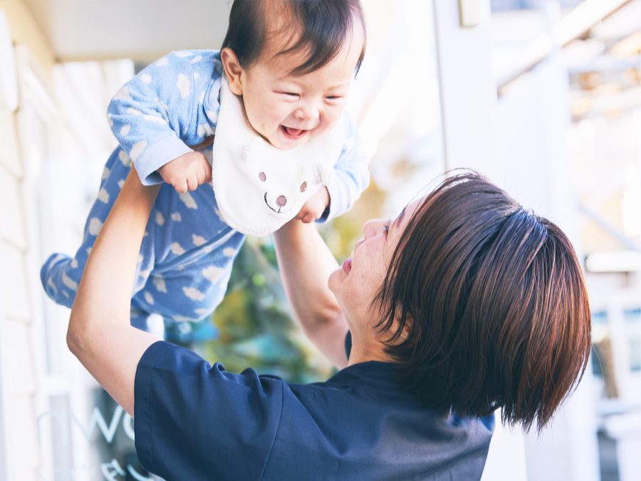 乳児を抱き上げる訪問看護師